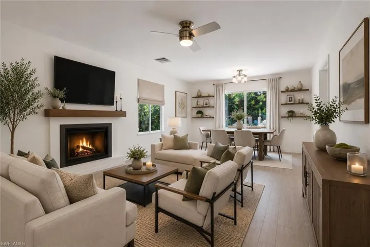 Virtually staged living and dining room, highlighting the wood burning fireplace. Access to the kitchen and patio/pool area.