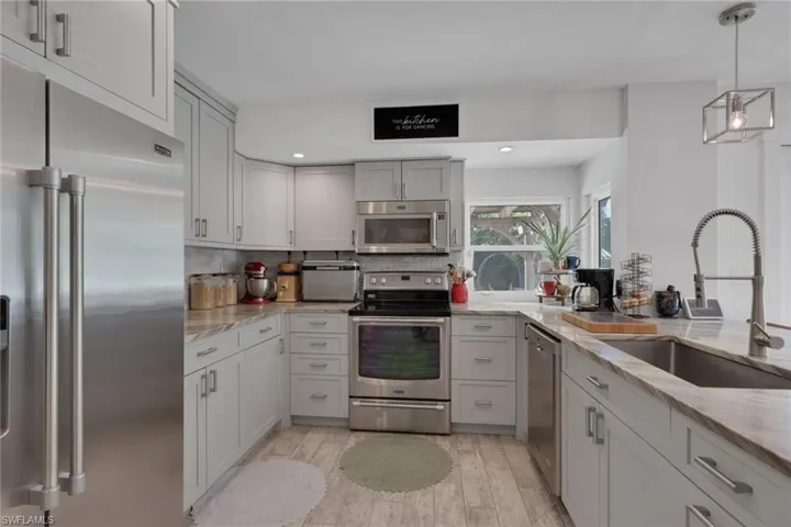 Beautifully updated kitchen with Quartz Countertops, gray wood shaker cabinets, stainless steel appliances, and a large walk in pantry