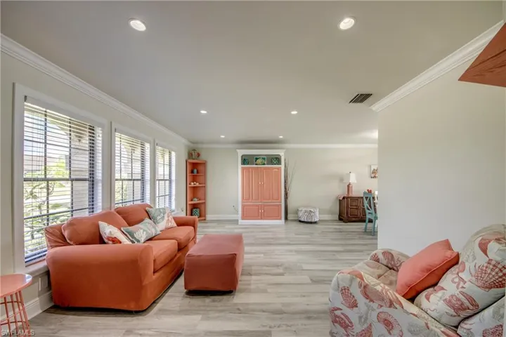 Living room featuring light wood-style floors, baseboards, ornamental molding, and recessed lighting