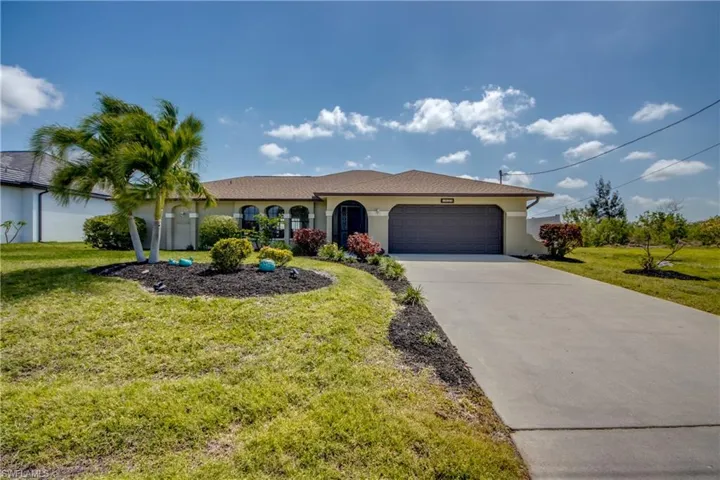 View of front of house with concrete driveway, stucco siding, a front yard, and a garage