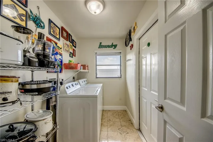Clothes washing area with independent washer and dryer, laundry area, light tile patterned floors, and baseboards