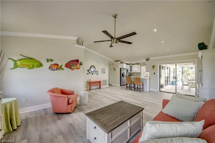 Living room featuring light wood-type flooring, ceiling fan, and ornamental molding