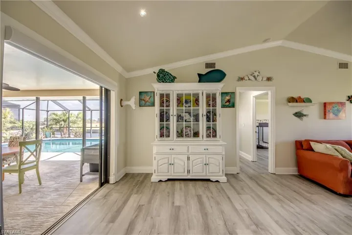 Doorway featuring light wood-type flooring, ornamental molding, visible vents, lofted ceiling, and a sunroom
