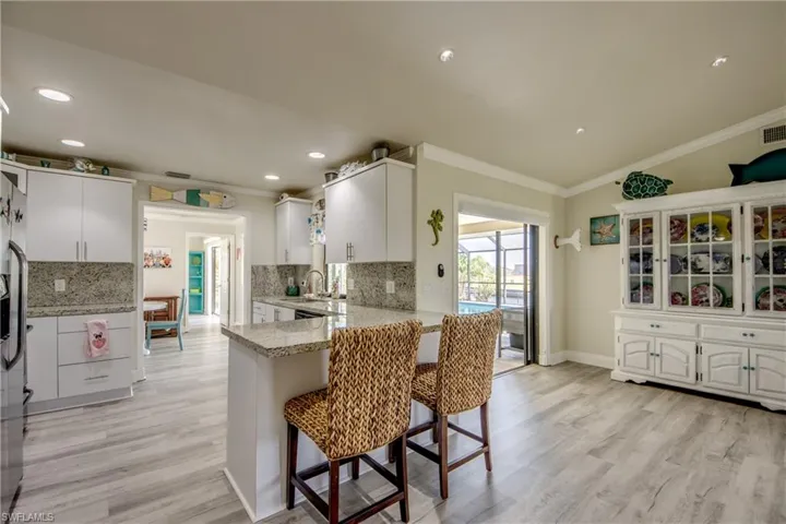 Kitchen featuring crown molding, light wood-type flooring, a breakfast bar, and a peninsula