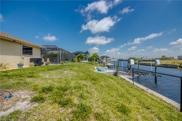 View of yard with central AC unit, a water view, boat lift, a dock, and a lanai