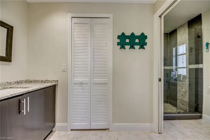 Full bathroom with a closet, baseboards, marble finish floor, and a stall shower