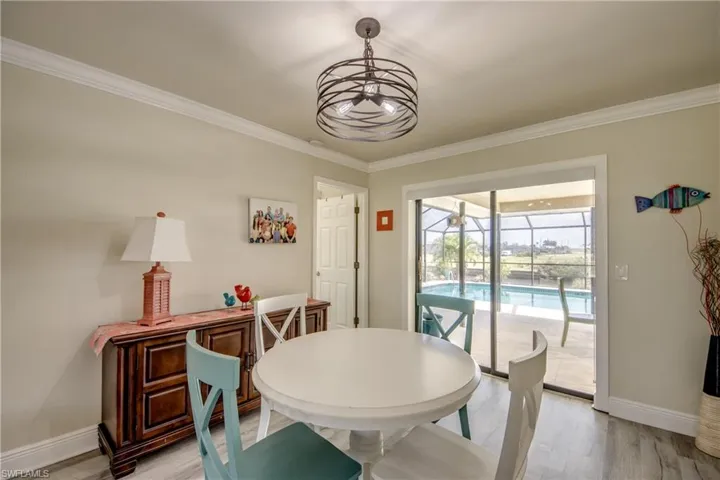 Dining area featuring baseboards, an inviting chandelier, a sunroom, ornamental molding, and light wood-style floors