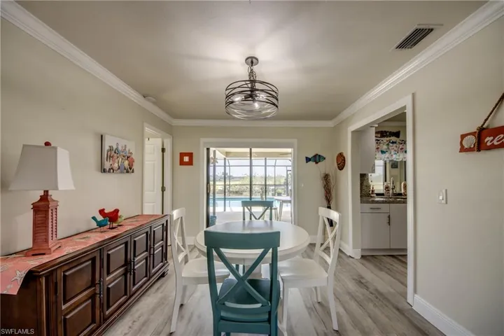 Dining space featuring visible vents, baseboards, an inviting chandelier, ornamental molding, and light wood finished floors