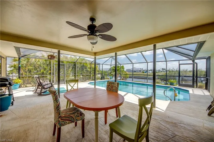Outdoor pool featuring a patio, glass enclosure, and ceiling fan
