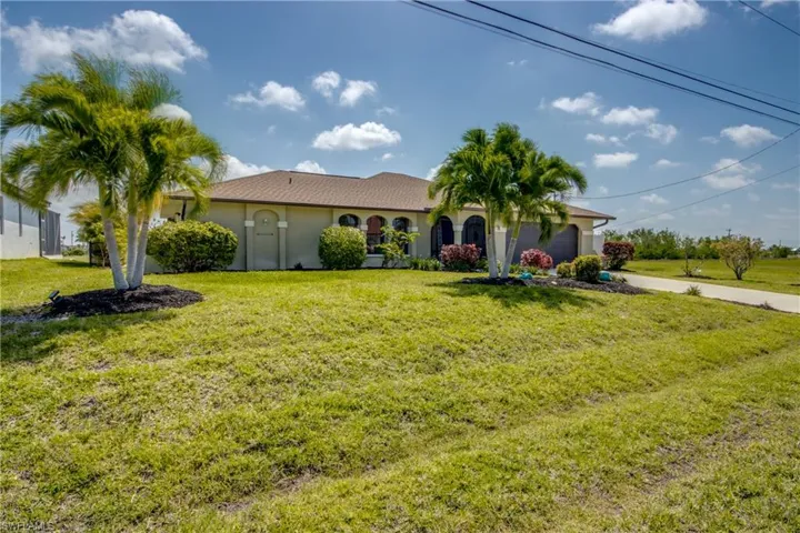 View of front of property with a garage, a front yard, driveway, and stucco siding