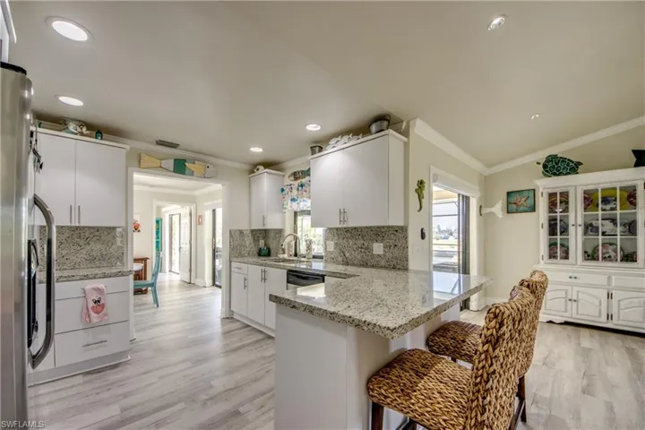 Kitchen with light wood-style flooring, a peninsula, ornamental molding, appliances with stainless steel finishes, and a breakfast bar area