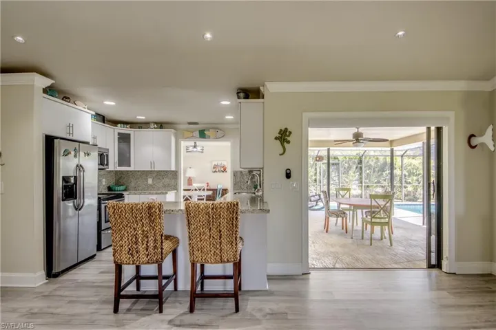 Kitchen with glass insert cabinets, ornamental molding, a peninsula, stainless steel appliances, and decorative backsplash