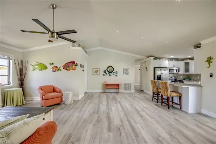 Living area with visible vents, ornamental molding, a ceiling fan, and light wood-style flooring