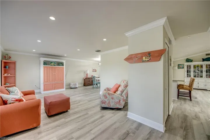 Living area featuring light wood-style flooring, baseboards, ornamental molding, and recessed lighting