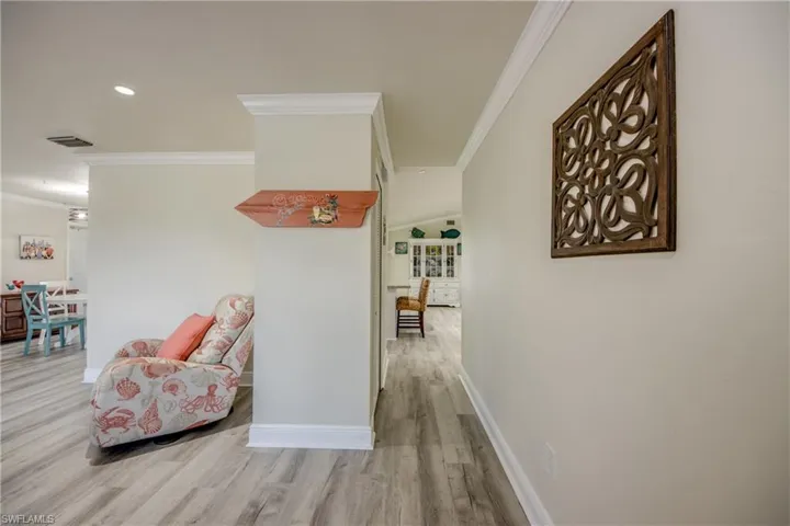 Corridor featuring crown molding, visible vents, baseboards, and wood finished floors