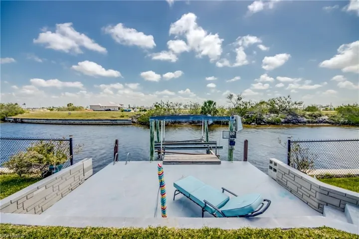 Dock area featuring boat lift, fence, and a water view