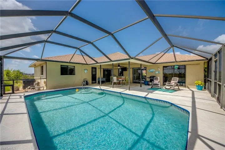Outdoor pool featuring ceiling fan, glass enclosure, and a patio