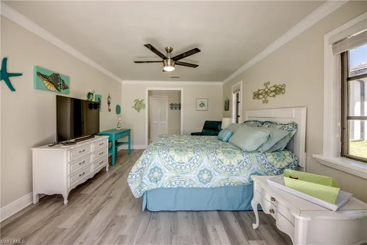 Bedroom with light wood finished floors, baseboards, and ornamental molding