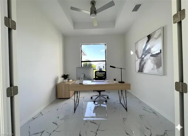 Office space with marble finish flooring, a tray ceiling, and a ceiling fan