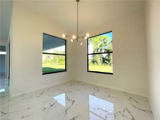 Unfurnished dining area featuring a chandelier and baseboards