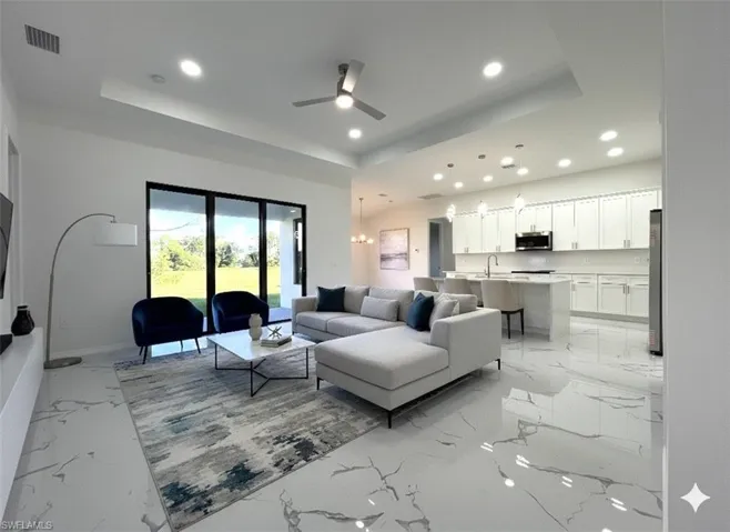 Living room featuring a raised ceiling, recessed lighting, a ceiling fan, and light marble finish flooring