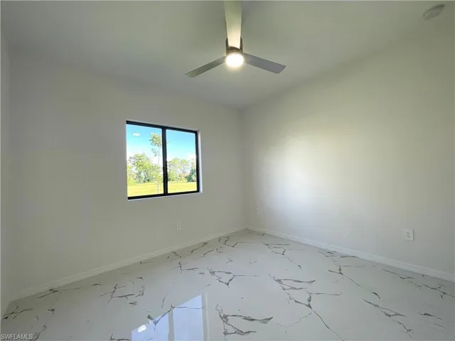 Unfurnished room featuring baseboards and light marble finish floors
