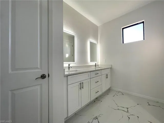 Full bath with double vanity and light marble finish floors