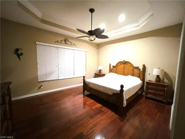Room featuring wood-finish flooring, a tray ceiling with recessed lighting, and a ceiling fan