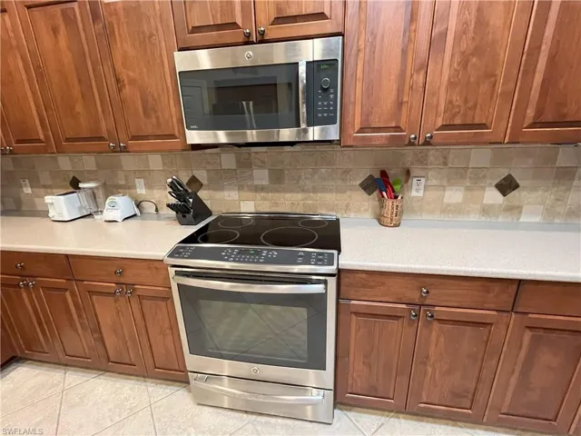Stainless steel Induction range and microwave oven with a tiled backsplash featuring decorative inserts