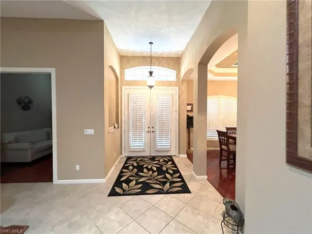 Foyer featuring vaulted ceilings, double doors with upper transom window, tile flooring, and arched doorways