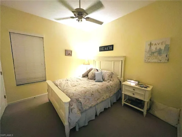 Bedroom featuring a ceiling fan with light fixture, window with blinds, and light-toned carpeting