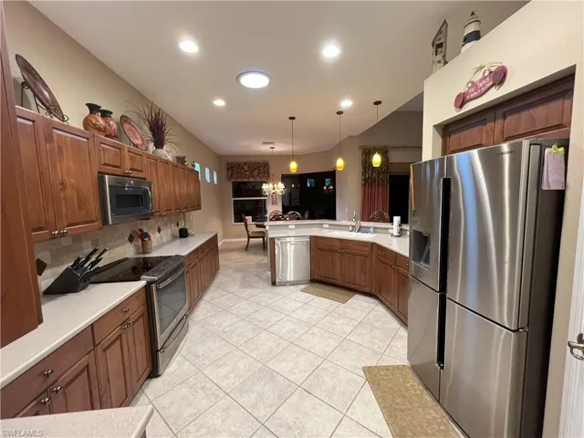 Spacious kitchen featuring extensive wood cabinetry, light-toned countertops, and stainless steel appliances