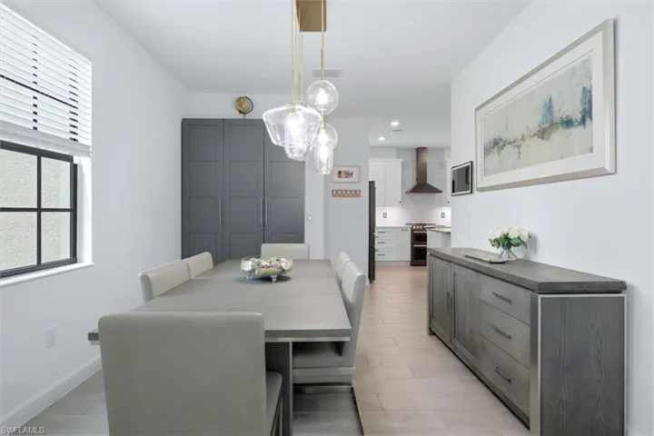Dining area featuring a modern chandelier, light wood-finish flooring, and a window with horizontal blinds