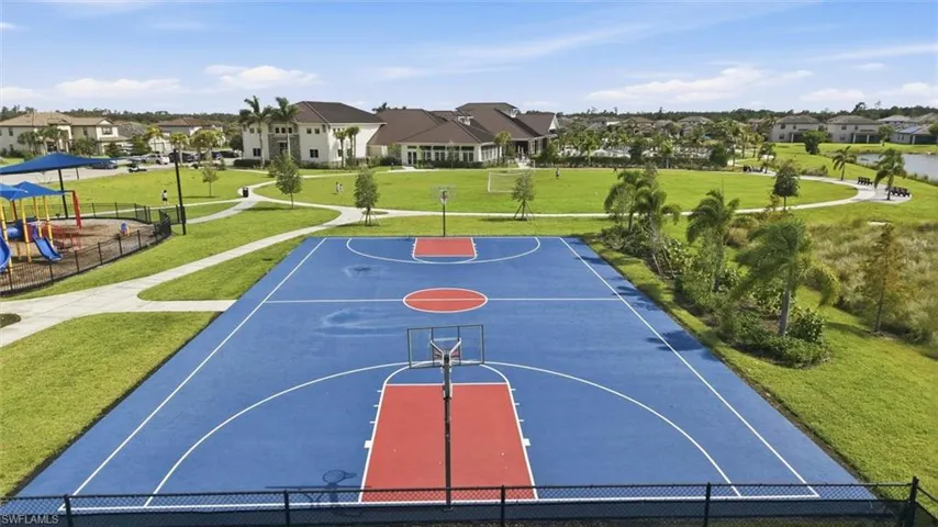 Multi-sport court featuring blue and red playing surfaces, surrounded by manicured green spaces