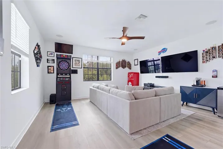 Spacious entertainment room featuring wood-finish flooring, recessed lighting, and a ceiling fan