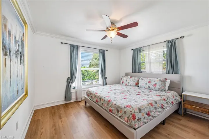 Bedroom with ornamental molding, wood-type flooring, and ceiling fan