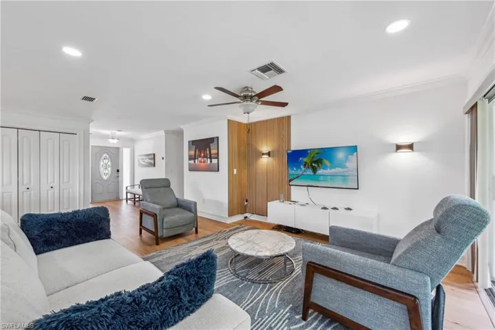 Living room featuring light wood-type flooring, ornamental molding, and ceiling fan