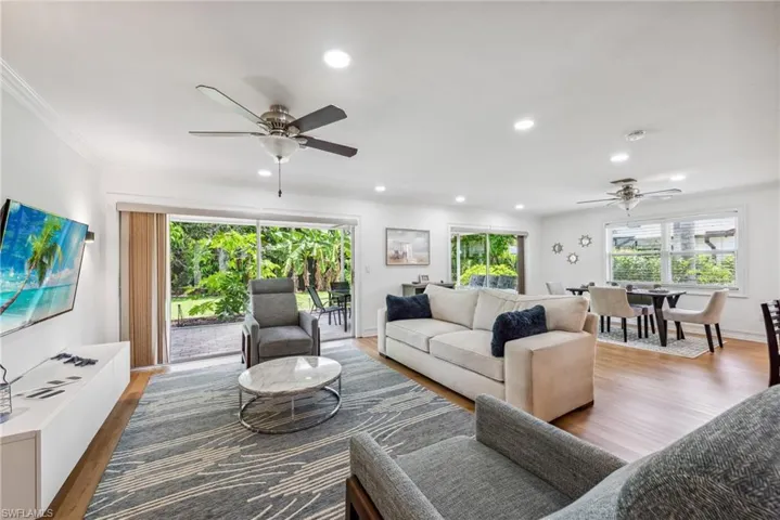 Living room with ceiling fan, light wood-type flooring, and ornamental molding