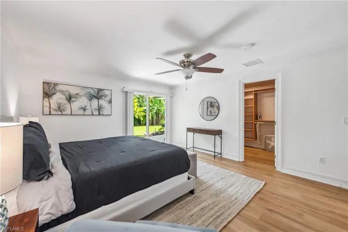 Bedroom featuring light hardwood / wood-style floors, a closet, crown molding, ceiling fan, and a walk in closet