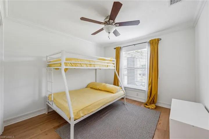 Bedroom featuring ceiling fan, crown molding, and wood-type flooring