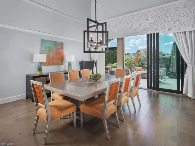 Dining room with wood finished floors, a chandelier, and a wall of windows