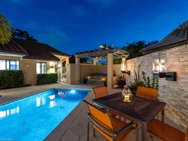 Pool at twilight featuring a patio area, a pergola, a jacuzzi, a gate, and outdoor dining space