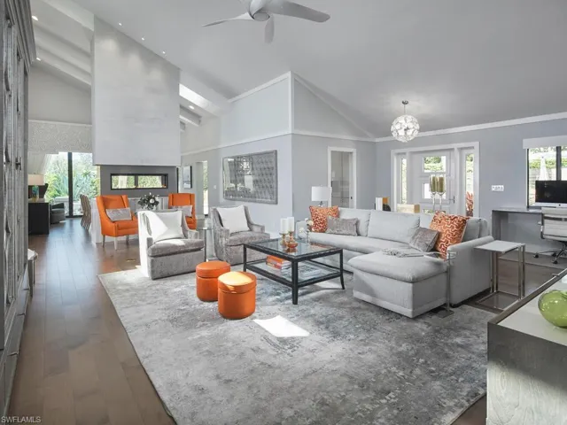 Living room with dark wood-style floors, a chandelier, high vaulted ceiling, a ceiling fan, and ornamental molding