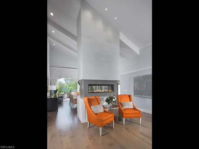 Sitting room featuring a multi sided fireplace, high vaulted ceiling, and recessed lighting