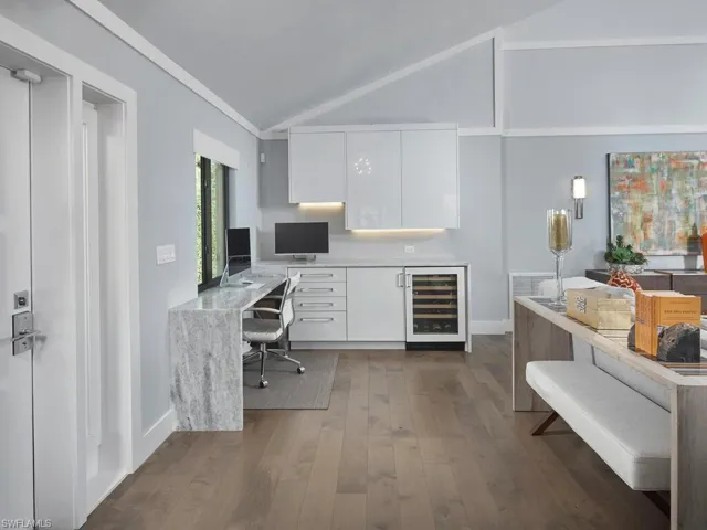 Office with built in desk, dark wood finished floors, wine cooler, vaulted ceiling, and ornamental molding