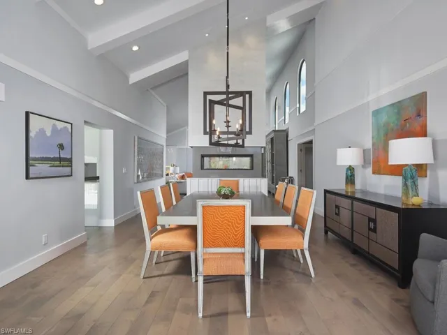 Dining space with hardwood / wood-style flooring, beamed ceiling, a towering ceiling, a chandelier, and recessed lighting