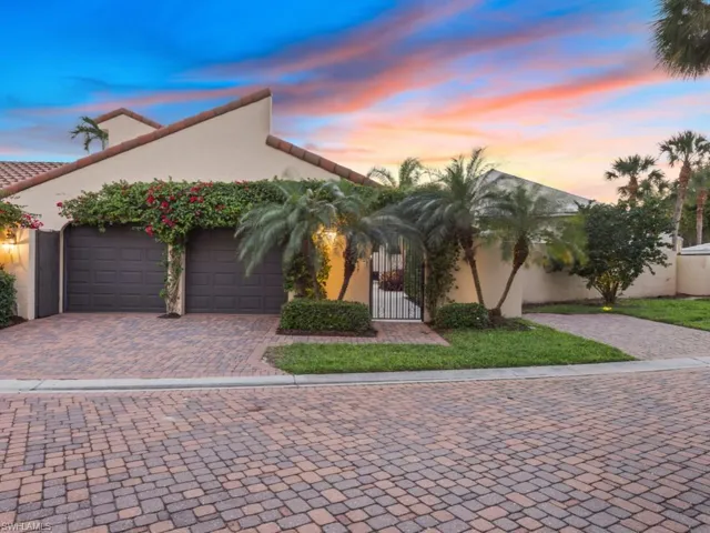 Mediterranean / spanish-style house with stucco siding, decorative driveway, a gate, and an attached garage
