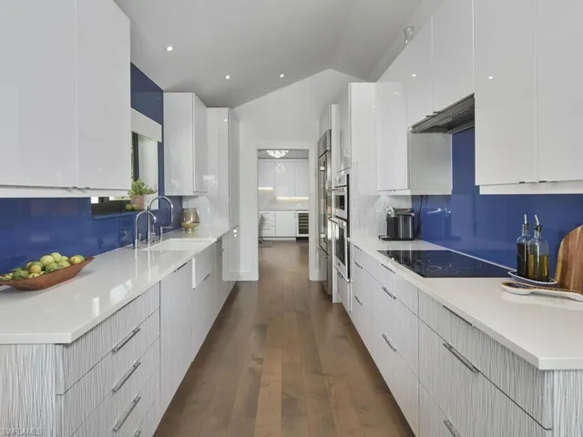 Kitchen with modern cabinets, decorative backsplash, white cabinets, vaulted ceiling, and dark wood-type flooring