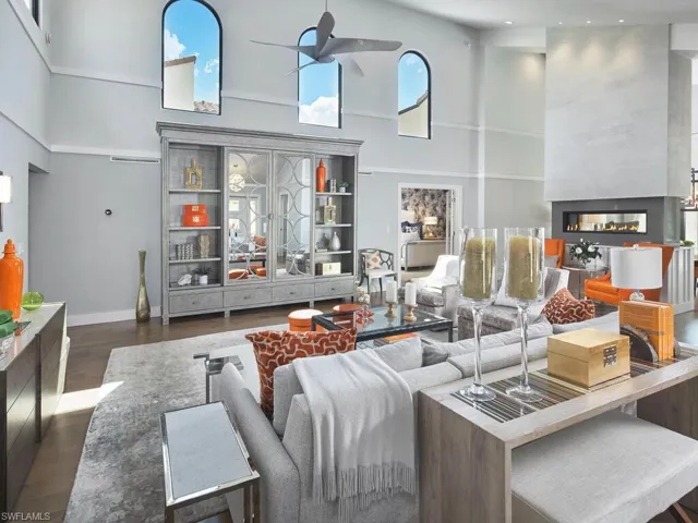 Living area featuring a high ceiling, dark wood-style floors, a multi sided fireplace, and ceiling fan
