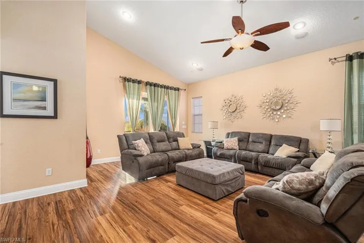 Living area with wood finished floors, lofted ceiling, a ceiling fan, and recessed lighting